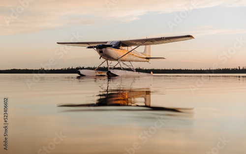 A seaplane float plane floats on a lake at sunset with soft lighting, the aircraft reflects in the calm waters of Candle Lake, in Northern Saskatchewan, Canada photo