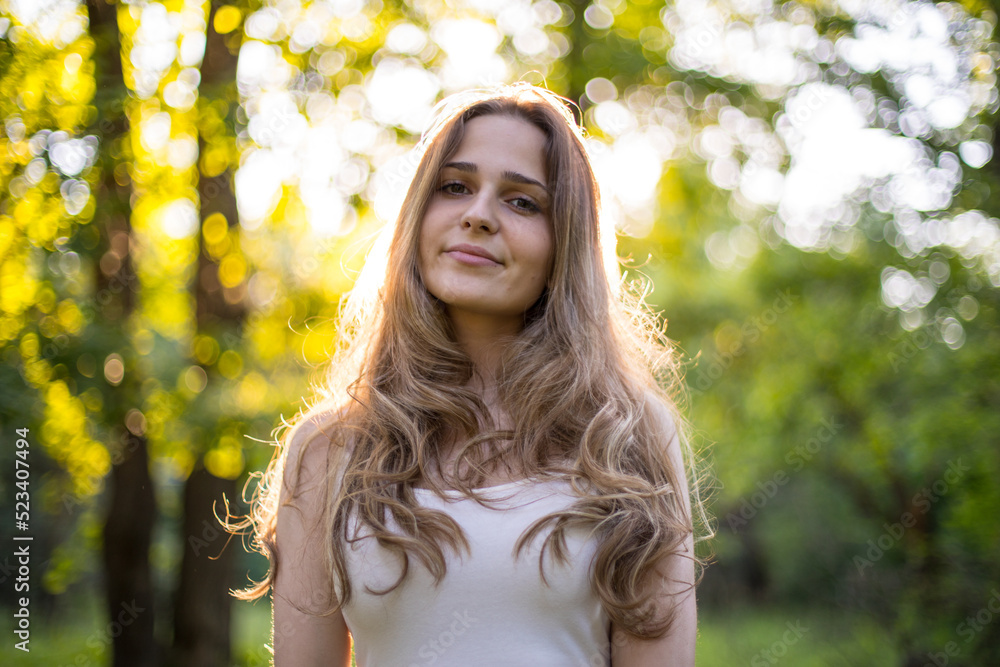 Beautiful young Russian girl dressed in a white dress, walks through the forest among the oaks in the rays of the sunset Beautiful young Russian girl dressed in a white dress, walks through the forest among the oaks in the rays of the sunset