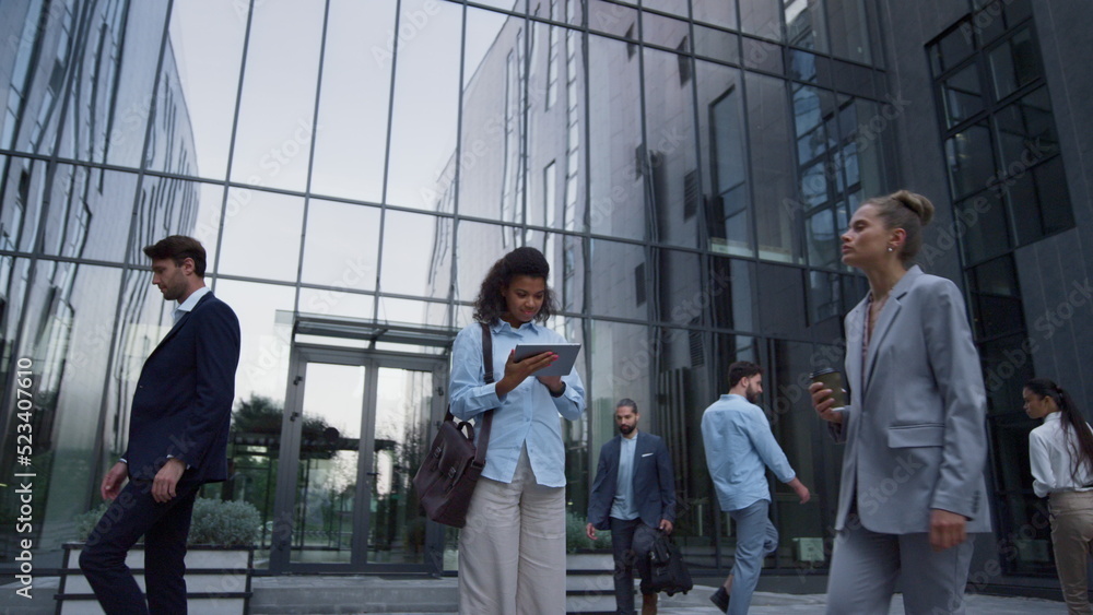 Focused woman use tablet in downtown area. Diverse employees rush to workplace. Focused woman use tablet in downtown area. Diverse employees rush to workplace.