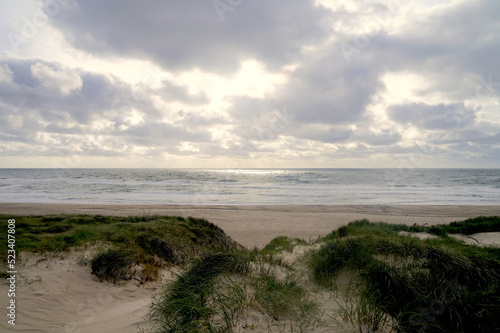 View from the dune of the beach and the raging waves of the North Sea at a almost cloudy evening on the Danish coast, Denmark, vacation, nature, environment, experience