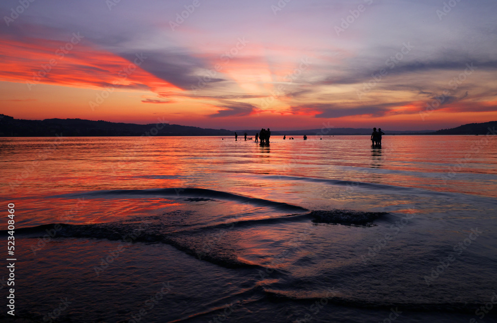 Naklejka premium Tourists at Sempach Lake in Switzerland, Europe. Sunset light.