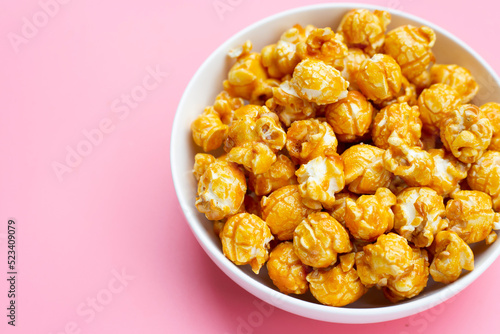 Honey caramel popcorn on pink background.