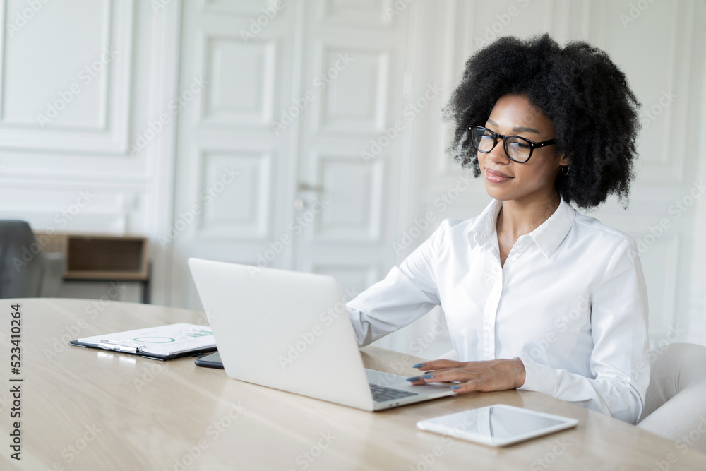 A female manager with glasses in formal clothes works in the office uses a laptop A female manager with glasses in formal clothes works in the office uses a laptop