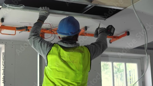 Hard male work on construction site. Two professional workers in special uniforms Contractors Safety Hats repairing ceiling wall inside building. Builders' equipment at workplace. industrial premises