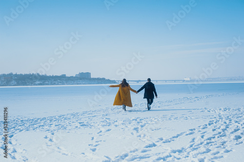 happy couple running on the snowy ice