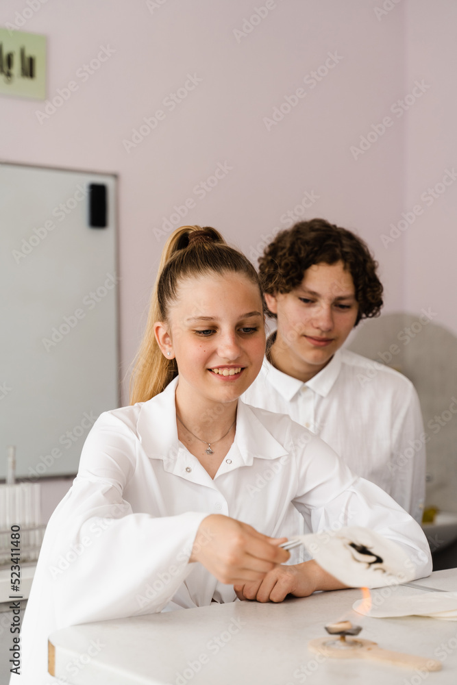 Education. Chemical experiments at a chemistry lesson at school. Children classmates hold test tubes and conduct experiments in the laboratory. Education. Chemical experiments at a chemistry lesson at school. Children classmates hold test tubes and conduct experiments in the laboratory.