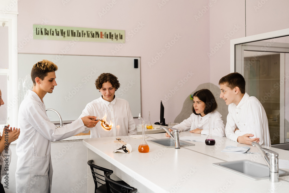 Fototapeta premium Chemistry lesson in labaratory. Education online in class with group of pupils studying on laptop, smiling and having fun together.
