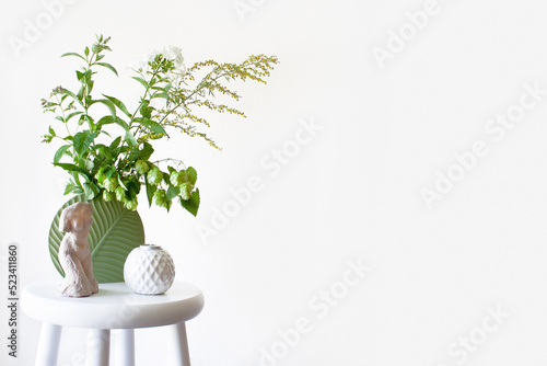 A bouquet of green herbs: wormwood, mint, hops and a sprig of phlox. Interior decor. Flowers, candle, clay figurine. Beautiful background. Space for text
