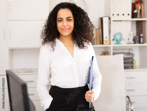 Fotografía Portrait of smiling young businesswoman holding clipboard inviting visitors to o