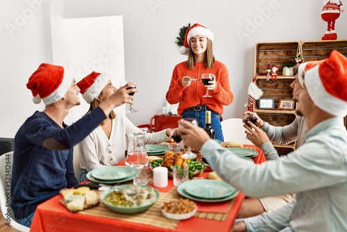 Group of young people smiling happy celebrating christmas toasting with wine at home.