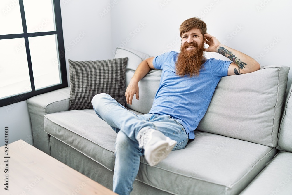 Young irish man smiling happy sitting on the sofa at home. Young irish man smiling happy sitting on the sofa at home.