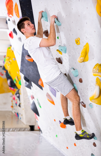 Sporty man training at bouldering gym without special climbing equipment