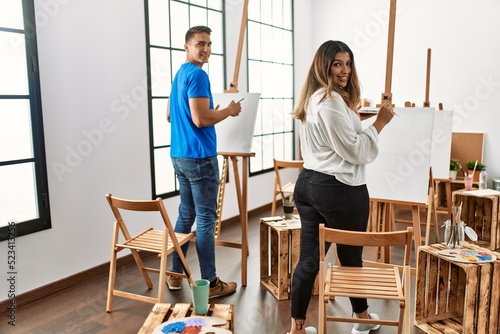 Two students smiling happy painting at art school.