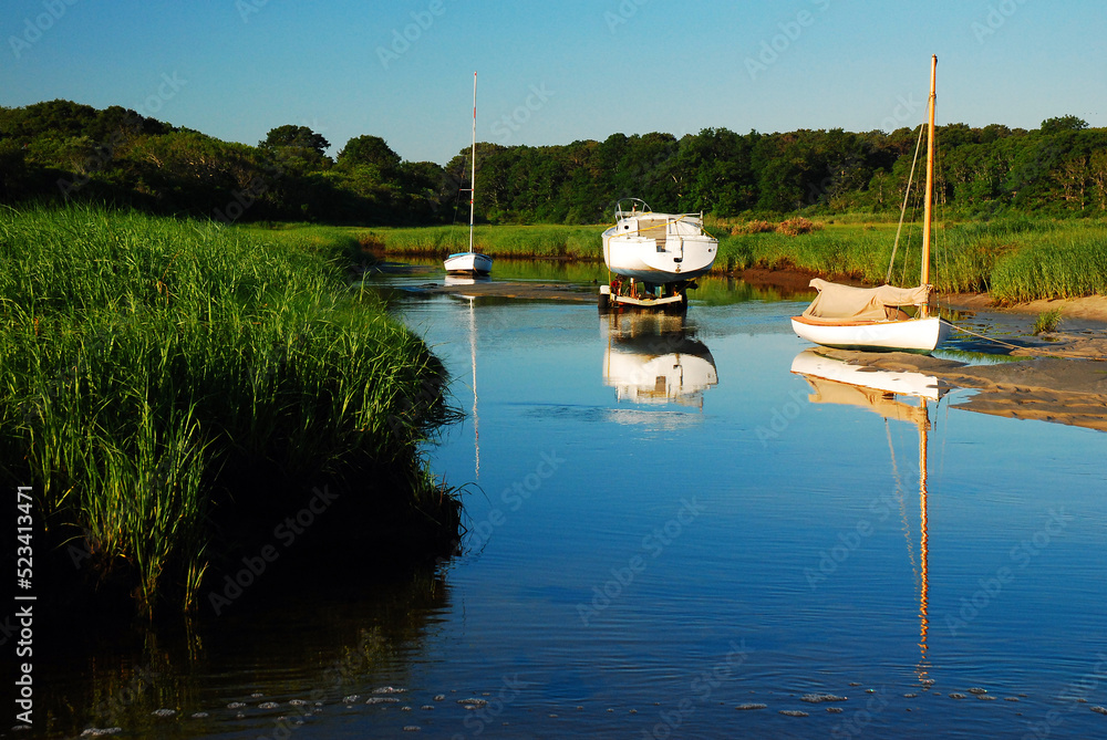 Fototapeta premium Boats are stranded on a sand bar at low tide in Brewster Creek Park, on Cape Cod