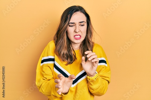 Young hispanic girl wearing casual clothes disgusted expression, displeased and fearful doing disgust face because aversion reaction.