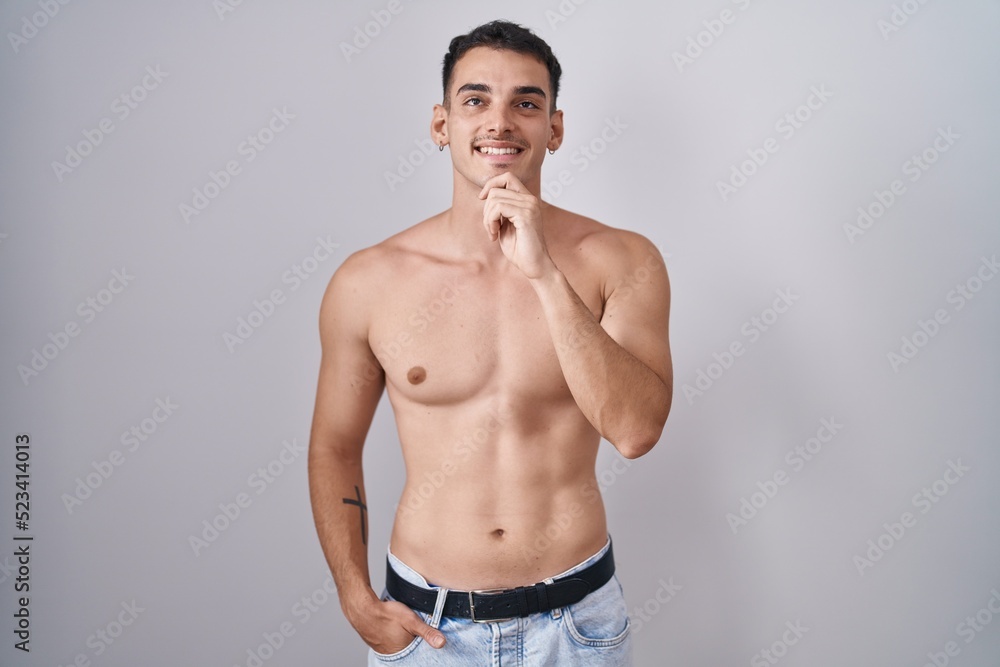 Handsome hispanic man standing shirtless with hand on chin thinking about question, pensive expression. smiling and thoughtful face. doubt concept.