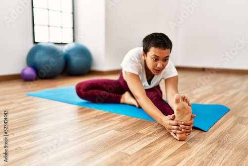 Young hispanic woman stretching at sport center