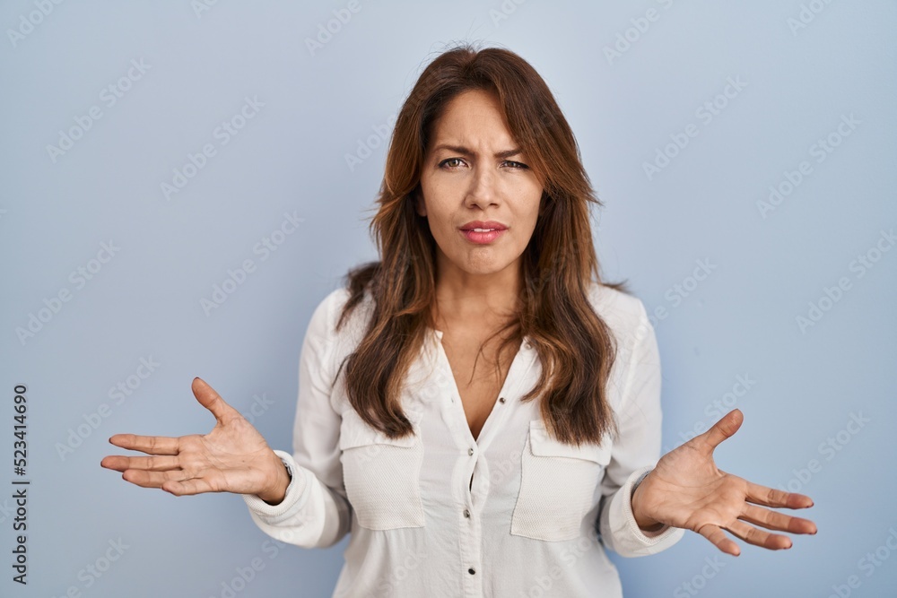 Hispanic woman standing over isolated background clueless and confused with open arms, no idea concept. Hispanic woman standing over isolated background clueless and confused with open arms, no idea concept.