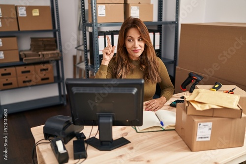 Hispanic woman working at small business ecommerce doing video call smiling with an idea or question pointing finger with happy face, number one