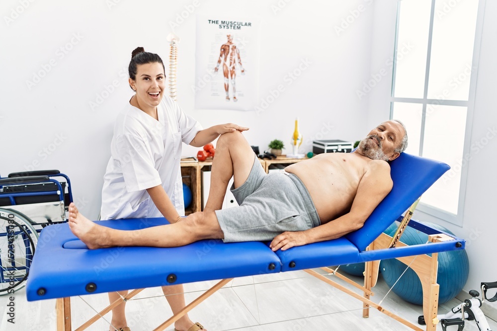 Physiotherapist and patient smiling confident having rehab session at clinic Physiotherapist and patient smiling confident having rehab session at clinic