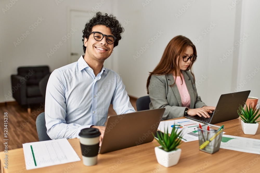 Two business workers smiling happy working using laptop at the office. Two business workers smiling happy working using laptop at the office.