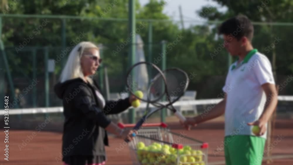 A woman and a young guy communicate on a tennis court A woman and a young guy communicate on a tennis court