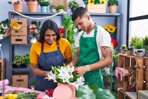 Man and woman florists smiling confident making bouquet of flowers at florist