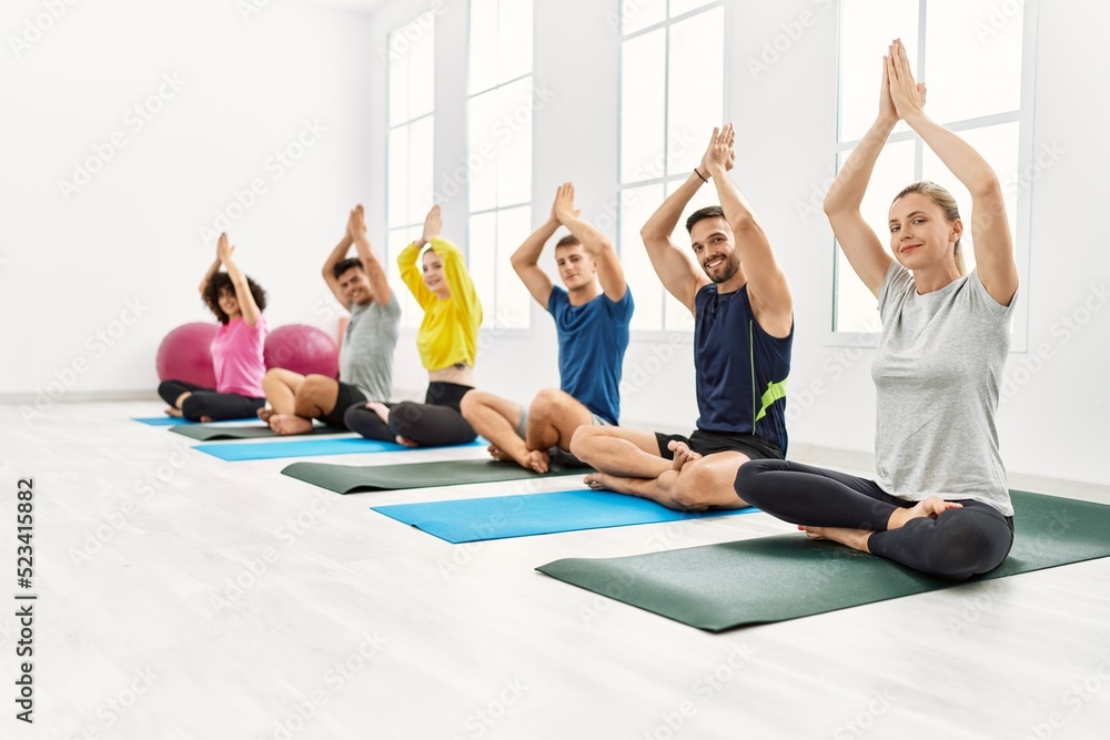 Group of young people smiling happy training yoga at sport center. Group of young people smiling happy training yoga at sport center.