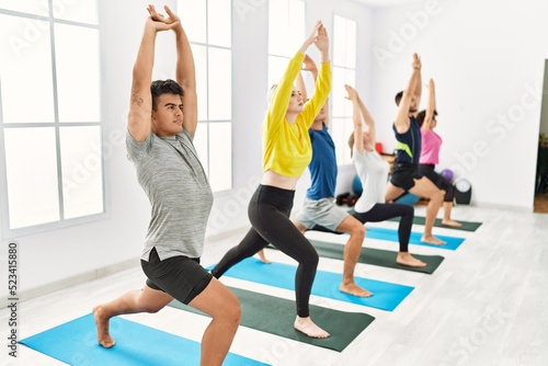 Group of young people concentrated training yoga at sport center.