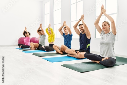 Group of young people smiling happy training yoga at sport center.