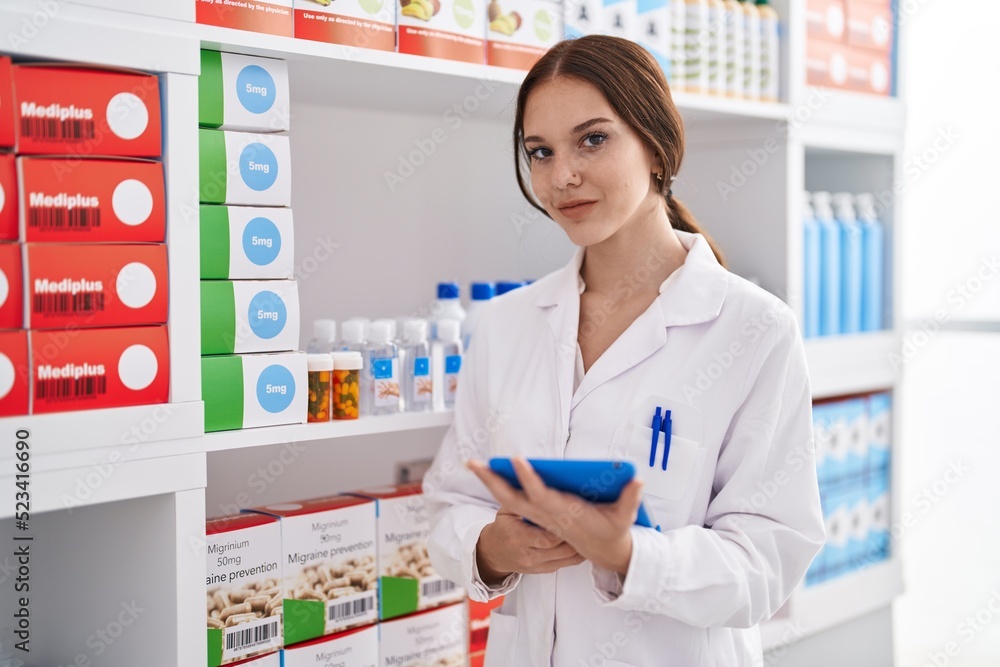 Young woman pharmacist using touchpad working at pharmacy