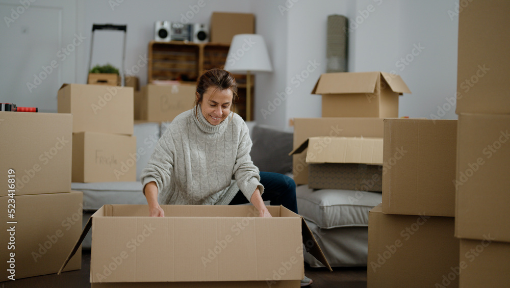 Middle age hispanic woman unboxing package at street Middle age hispanic woman unboxing package at street