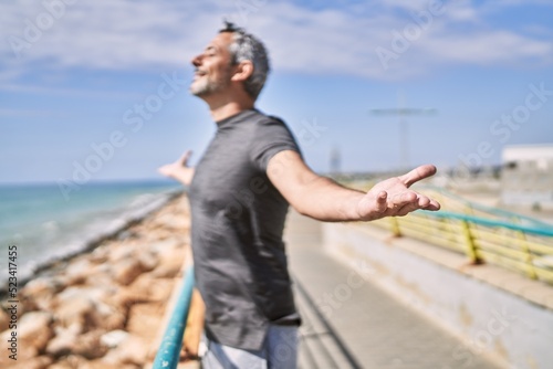 Middle age hispanic man wearing sportswear breathing at seaside