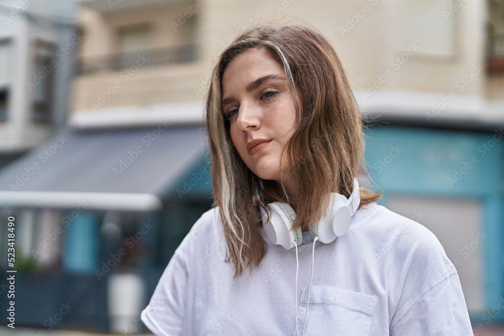 Young woman with relaxed expression wearing headphones at street