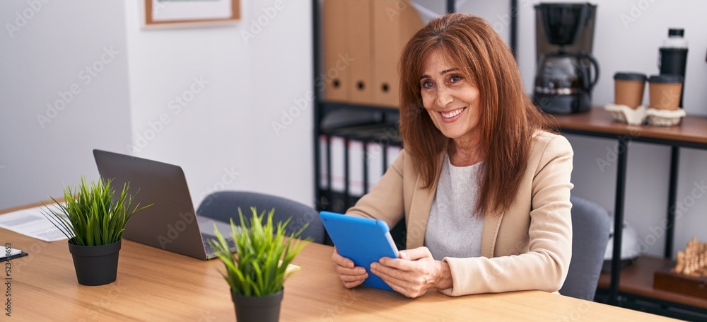 Middle age woman business worker using touchpad working at office Middle age woman business worker using touchpad working at office