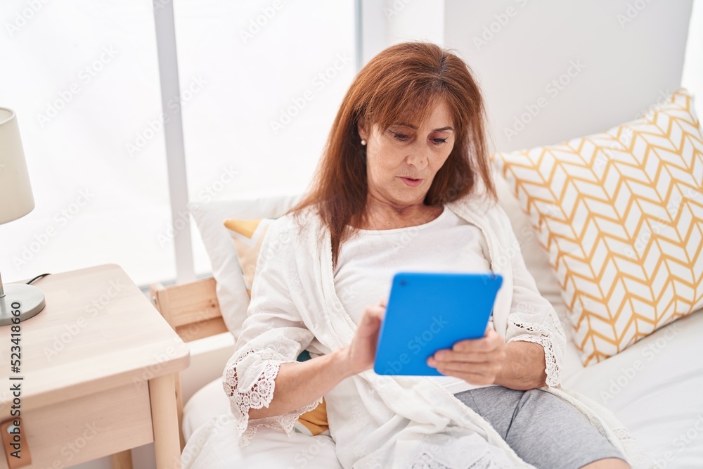 Middle age woman using touchpad sitting on bed at bedroom Middle age woman using touchpad sitting on bed at bedroom