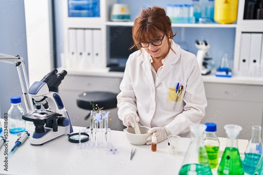 Middle age woman scientist smiling confident holding syrup treatment at laboratory Middle age woman scientist smiling confident holding syrup treatment at laboratory