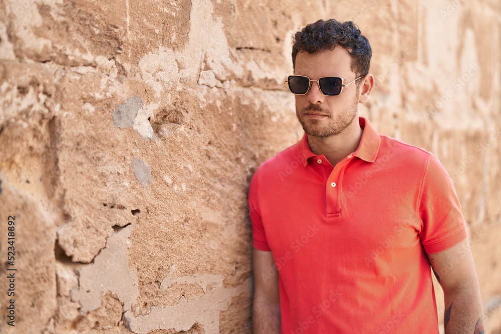 Young hispanic man with relaxed expression wearing sunglasses at street Young hispanic man with relaxed expression wearing sunglasses at street