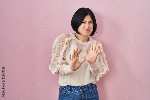Foto Young asian woman standing over pink background disgusted expression, displeased and fearful doing disgust face because aversion reaction