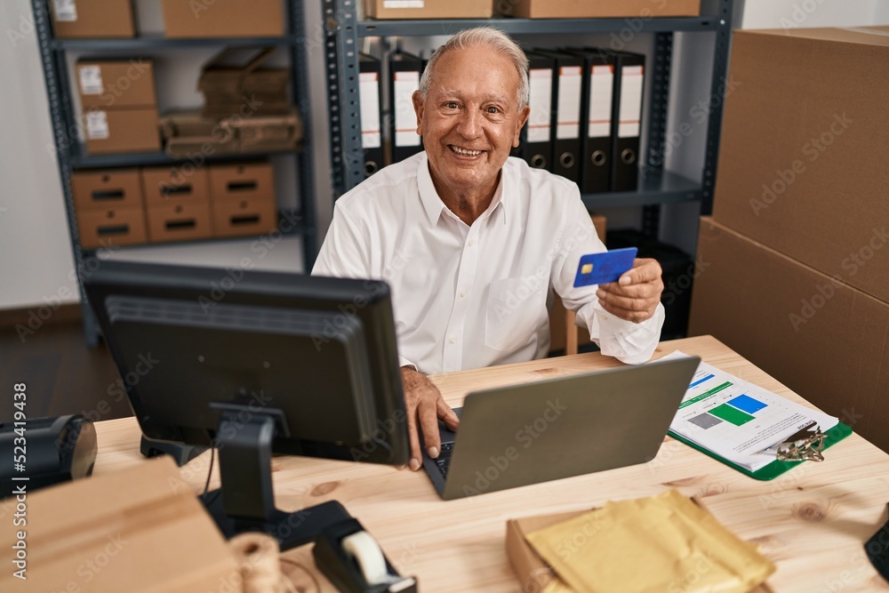 Senior man ecommerce business worker using laptop and credit card at office Senior man ecommerce business worker using laptop and credit card at office