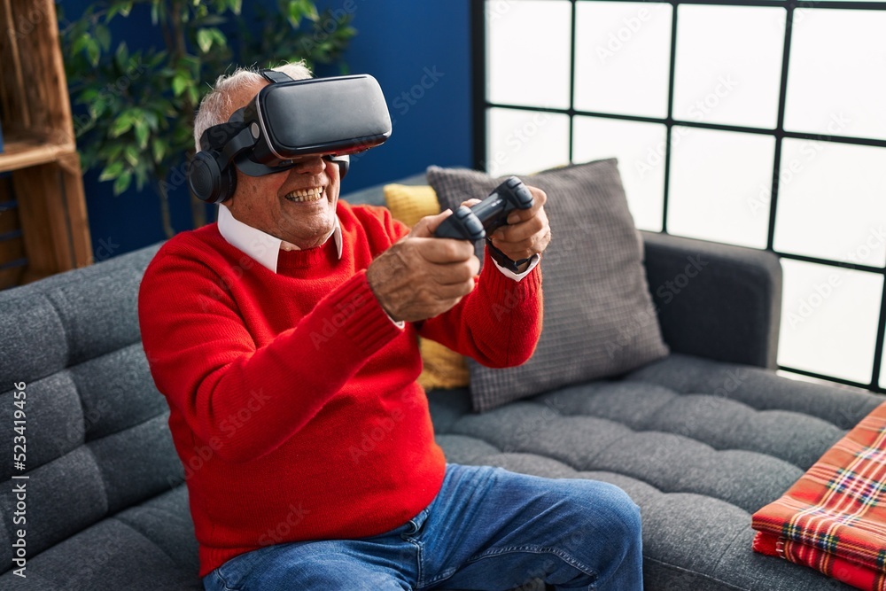 Senior man playing video game using virtual reality goggles at home Senior man playing video game using virtual reality goggles at home