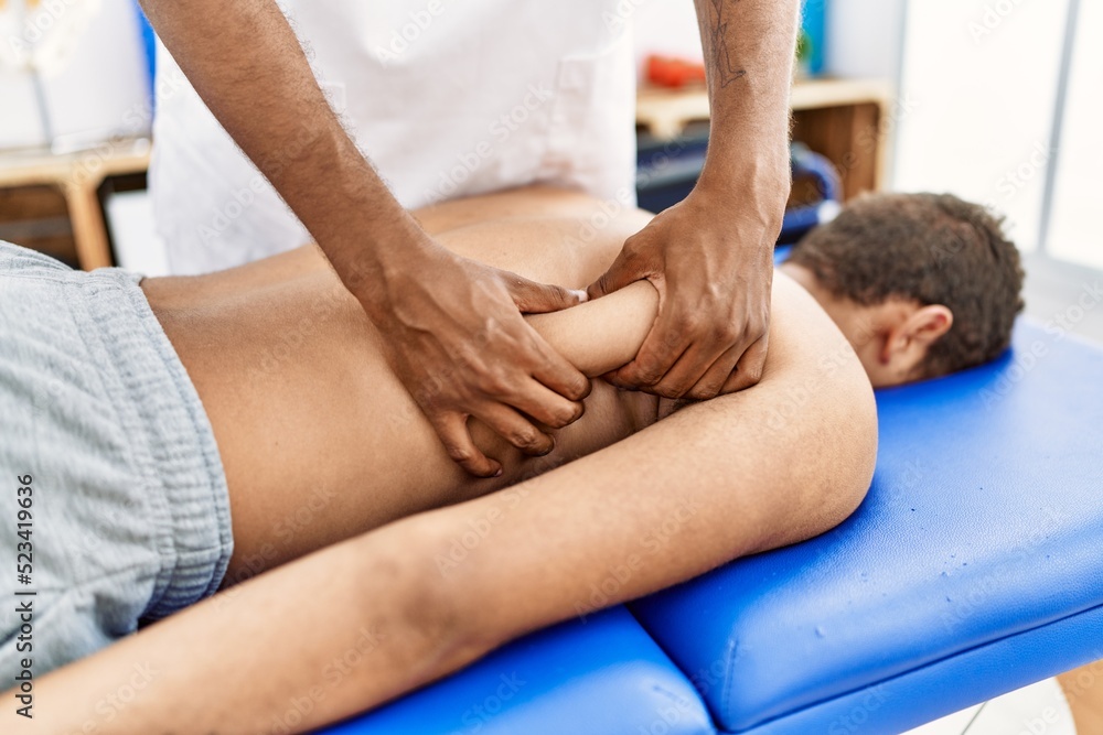 Fototapeta premium Two men physiptherapist and patient having rehab session massaging back at clinic