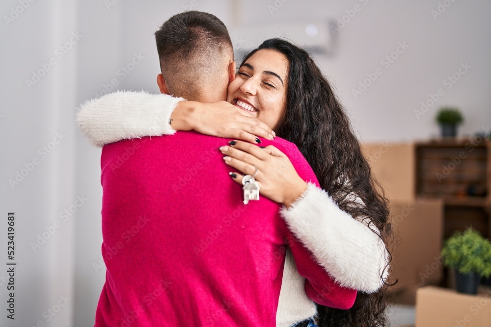 Man and woman couple hugging each other holding key at new home Man and woman couple hugging each other holding key at new home