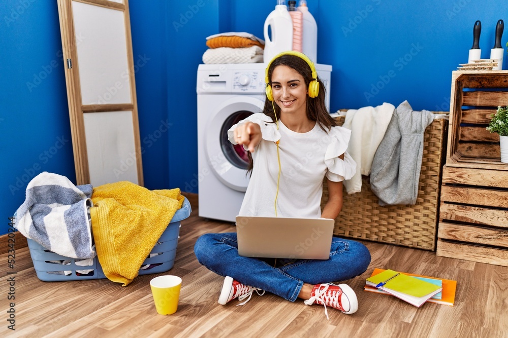Young hispanic woman studying while waiting for laundry pointing to you and the camera with fingers, smiling positive and cheerful Young hispanic woman studying while waiting for laundry pointing to you and the camera with fingers, smiling positive and cheerful
