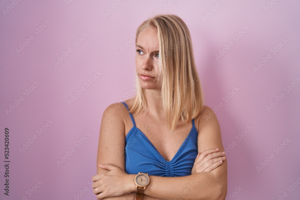 Young caucasian woman standing over pink background looking to the side with arms crossed convinced and confident Young caucasian woman standing over pink background looking to the side with arms crossed convinced and confident