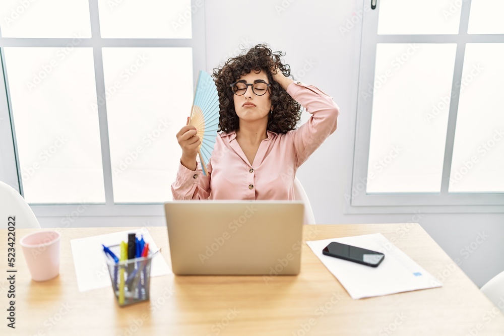 Young middle east businesswoman using hand fan at the office. Young middle east businesswoman using hand fan at the office.