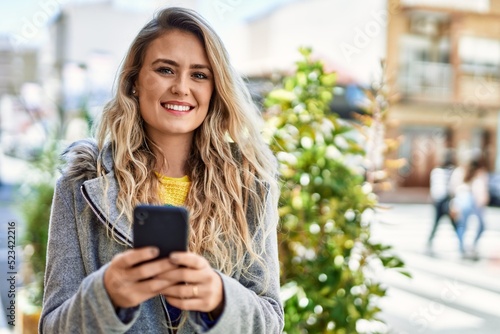 Young blonde woman using smartphone at the city