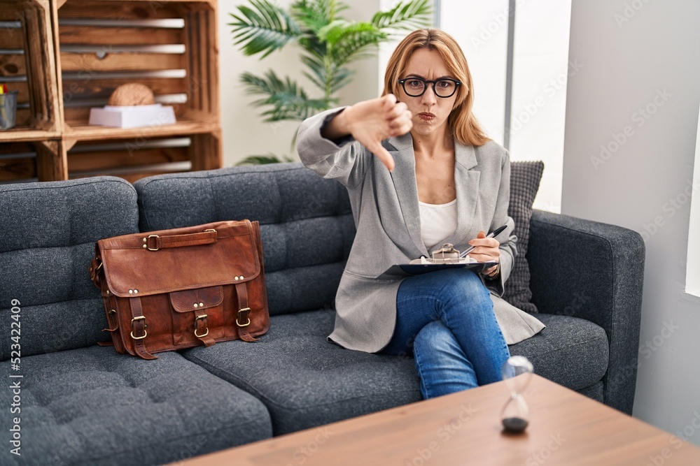 Hispanic woman working at consultation office looking unhappy and angry showing rejection and negative with thumbs down gesture. bad expression. Hispanic woman working at consultation office looking unhappy and angry showing rejection and negative with thumbs down gesture. bad expression.
