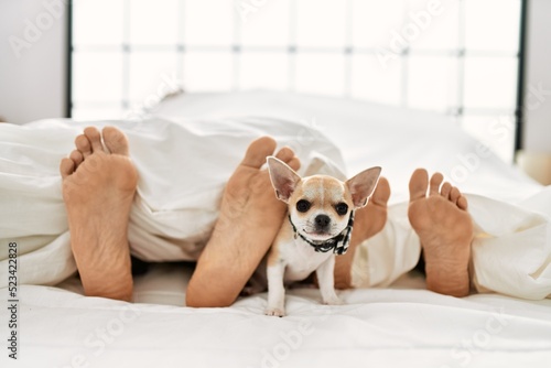Couple feet and dog on bed. photo
