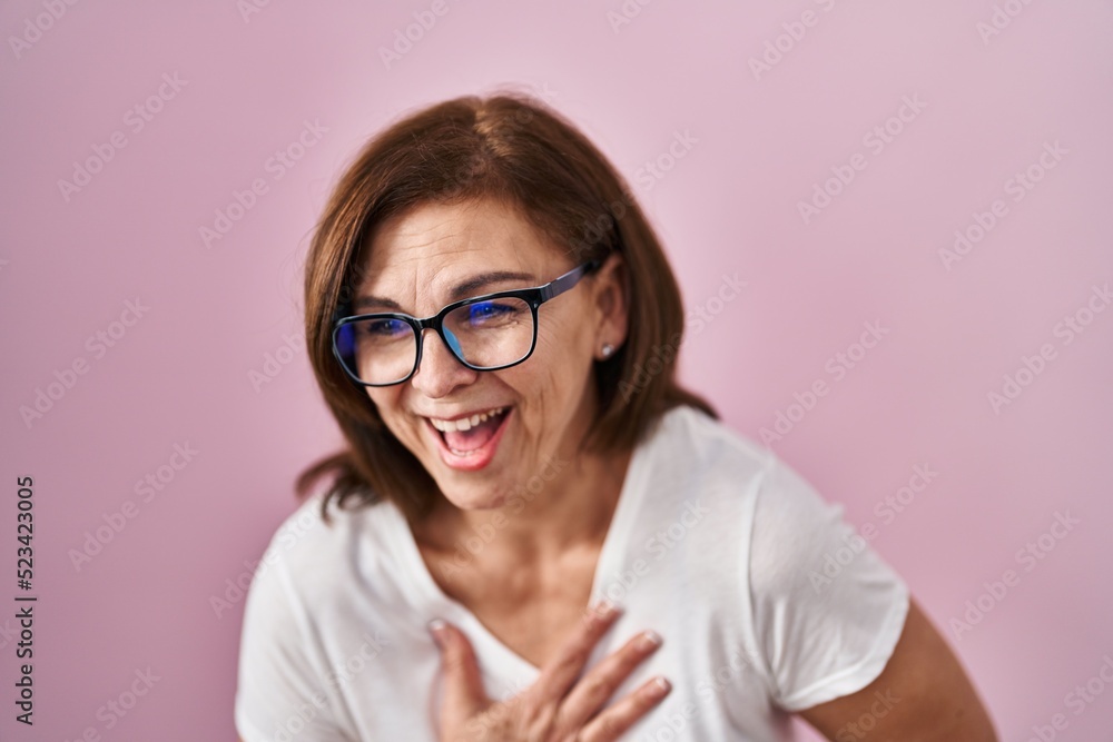 Middle age hispanic woman standing over pink background smiling and laughing hard out loud because funny crazy joke with hands on body.